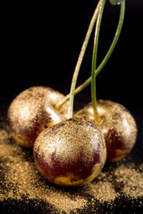 Gold fruits on black background close up 