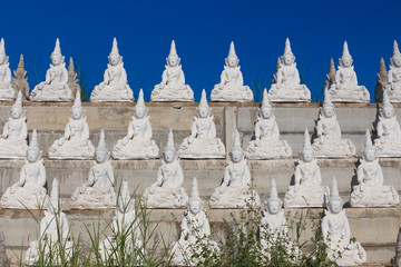 raw of white buddha status on the wall