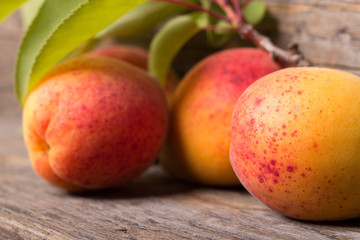Apricots with leaf on wooden background with water drop