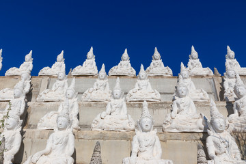 raw of white buddha status on the wall