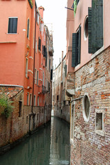 narrow navigable canal between the tall houses of Venice in Ital
