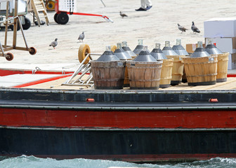 Naklejka premium carboys full of wine carried in a boat in Venice