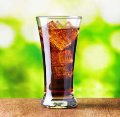 Glass of cola with ice on nature background