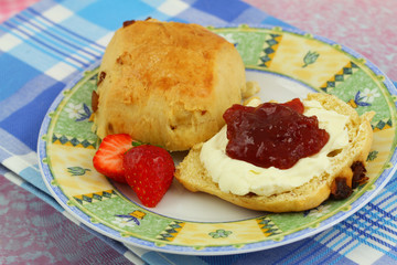 Scone with strawberry jam and clotted cream, close up