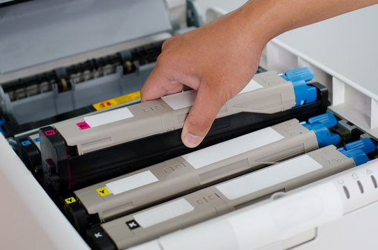 Male hand holding and puts color toner to printer.
