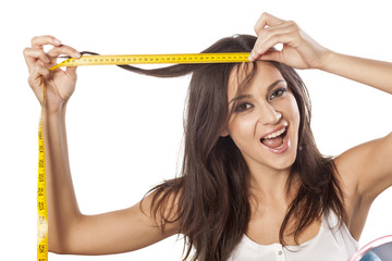 Happy attractive girl measured her hair with a tape measure