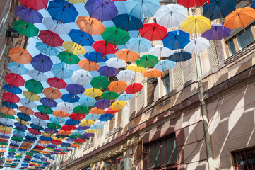 Fototapeta premium Ulica ozdobiona kolorowymi parasolami i ścianą