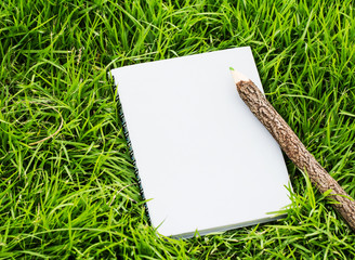 Pencil and notebook on grass