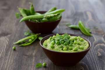 Mashed green peas and potatoes in a bowl on a wooden table