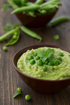 Mashed green peas and potatoes in a bowl on a wooden table