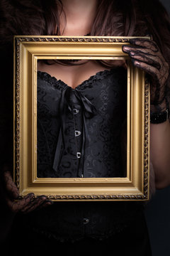 woman wearing corset and fur and holding vintage golden frame