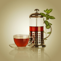 Cup of tea and teapot with mint leaf