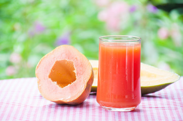 Papaya juice on wooden table with flower garden background