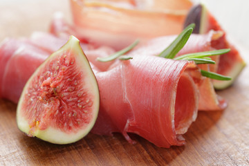 dried jamon slices with figs on wood table
