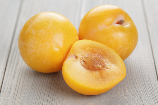 three yellow plums on rustic table