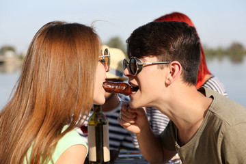 Young couple eating sausage on picnic, outdoors