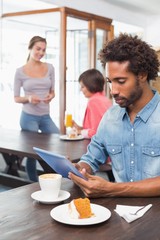 Handsome man using tablet while having coffee