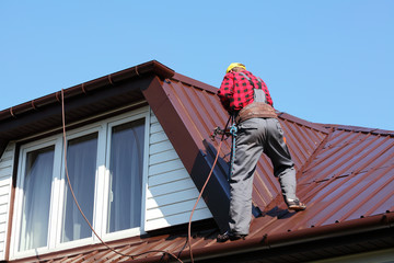 roofer builder worker spraying paint on roof