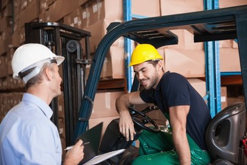 Warehouse manager talking with forklift driver