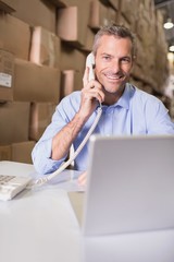 Warehouse manager using telephone and laptop