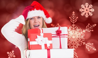Composite image of festive blonde holding pile of gifts