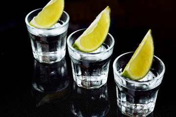 Tequila with lime on black background