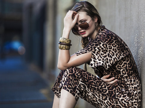 Weak woman sitting in the city and wearing a leopard-skin dress
