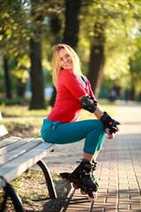 Beautiful young woman in roller skates sitting on park bench