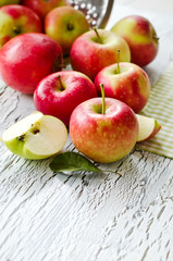 Red fresh apples from garden with leaves on white wooden backgro