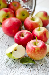 Juicy fresh apples from garden with leaves on wooden background