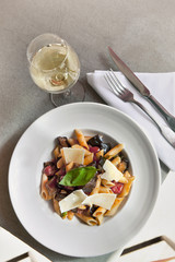 Pasta, parmesan and vegetables on a plate, glass of white wine