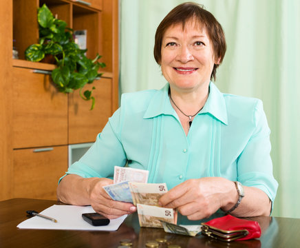 Portrait of happy female pensioner with cash and bills