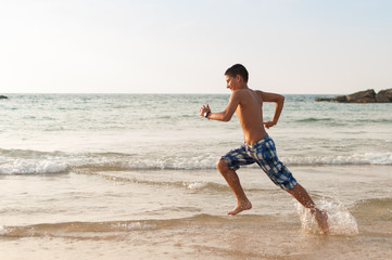 Fototapeta na wymiar Teen boy is running along the beach