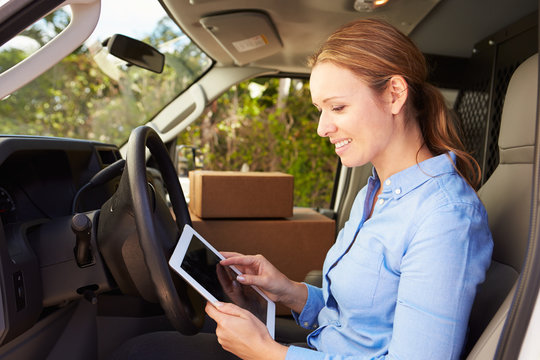 Female Delivery Driver Sitting In Van Using Digital Tablet