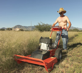 A Shirtless Cowboy Operates a Brush Mower on the Ranch