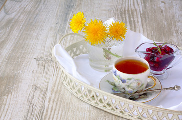 cup of tea with jam on a tray on a white wooden background