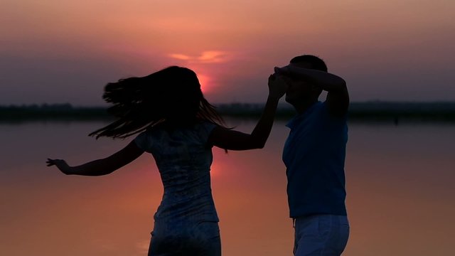 Silhouette man and woman dancing at sunset. Slow motion.