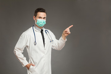 Male doctor in surgical mask pointing