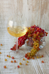 glass of white wine and fresh grapes on a wooden background