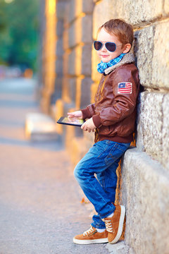 fashionable boy with digital tablet near the wall