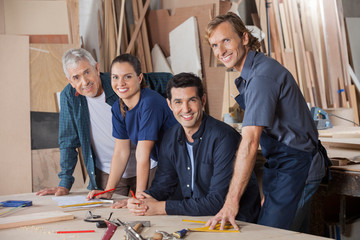 Confident Carpenters Working At Workshop Table