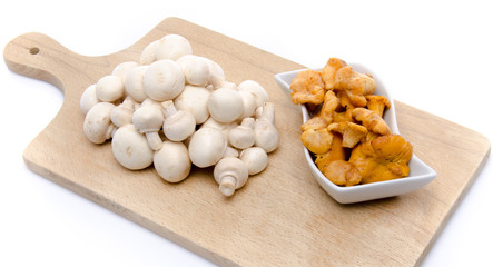White button and chanterelle mushrooms on a wooden board