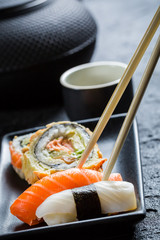 Sushi in a black ceramic eaten with chopsticks