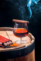 Aroma of Cuban cigars and cognac on black background