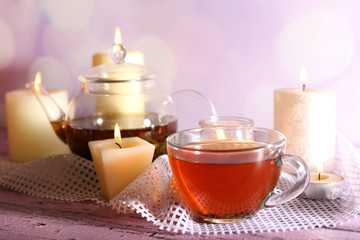 Composition with tea in cup and teapot and candles