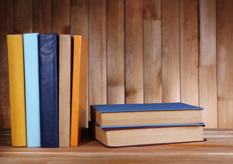 Books on wooden table on wooden wall background