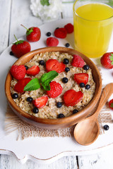 Tasty oatmeal with berries on table close-up