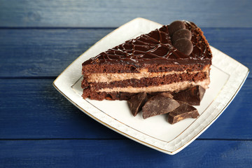 Chocolate cake on plate on color wooden background