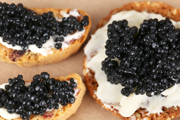 Slices of bread with butter and black caviar on paper