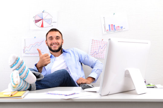 Confident Businessman Holding His Legs In Funny Socks On Desk